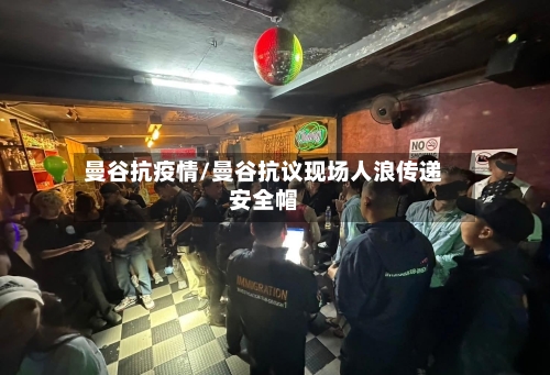 曼谷抗疫情/曼谷抗议现场人浪传递安全帽